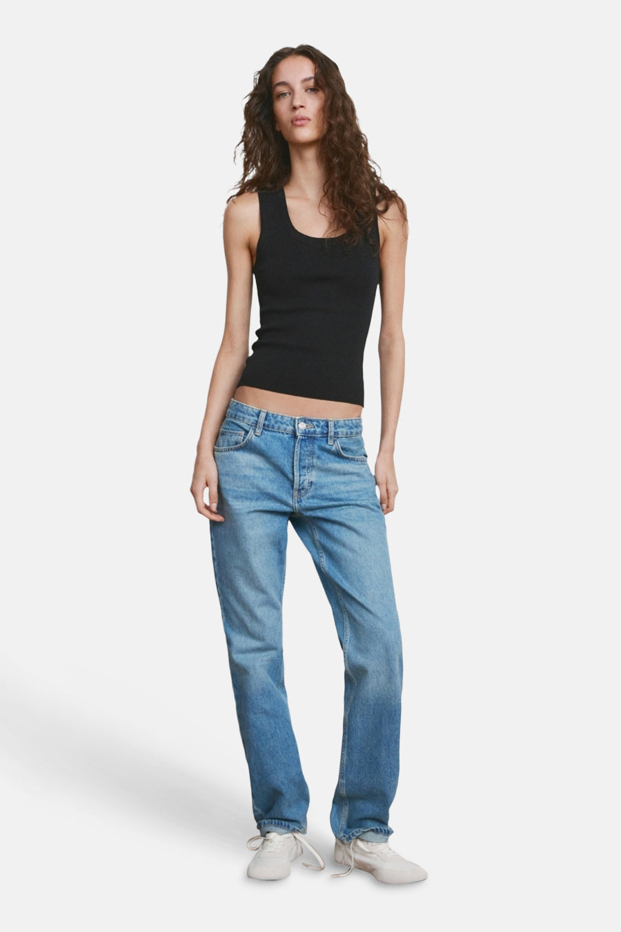 Haut noire de MANGO, avec une texture côtelée et combinée avec un jean bleu et des baskets blanches.