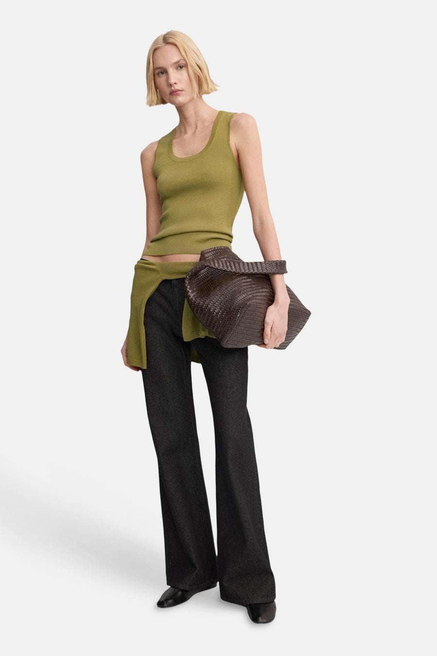 Débardeur kaki de MANGO, à la coupe ajustée, associé à un jean foncé ample et un sac tissé marron.