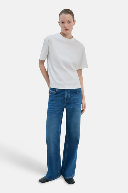 T-shirt blanc de MANGO, à manches courtes et coupe droite, combiné avec un jean bleu et des chaussures noires.