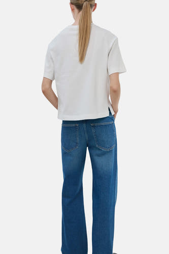 Wit T-shirt van MANGO, met korte mouwen en rechte pasvorm, gezien van achteren, gecombineerd met blauwe jeans.
