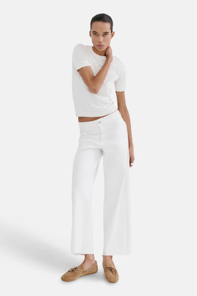 Jean large blanc de MANGO, associé à un t-shirt blanc et des chaussures marron.
