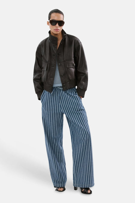Pantalon bleu de MANGO, à rayures verticales, combiné avec une veste en cuir et des lunettes de soleil.