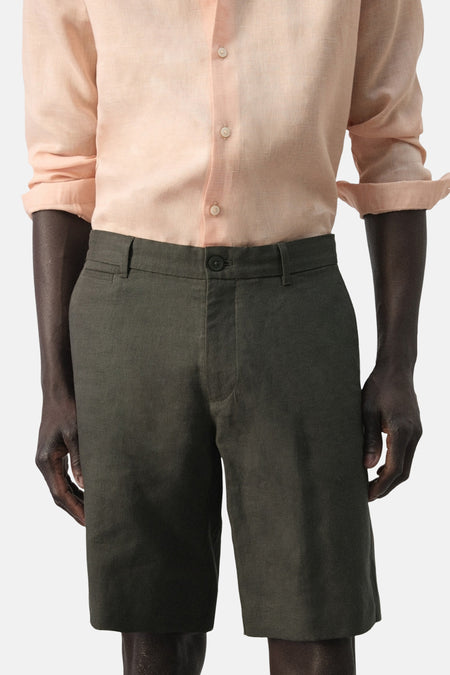 Bermuda de MANGO, de couleur unie et à la coupe décontractée, combinée avec une chemise en lin couleur pêche.