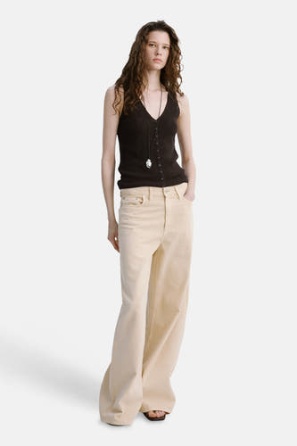 Haut marron sans manches de MANGO avec fermeture à boutons, portée avec une chaîne et un pantalon beige.