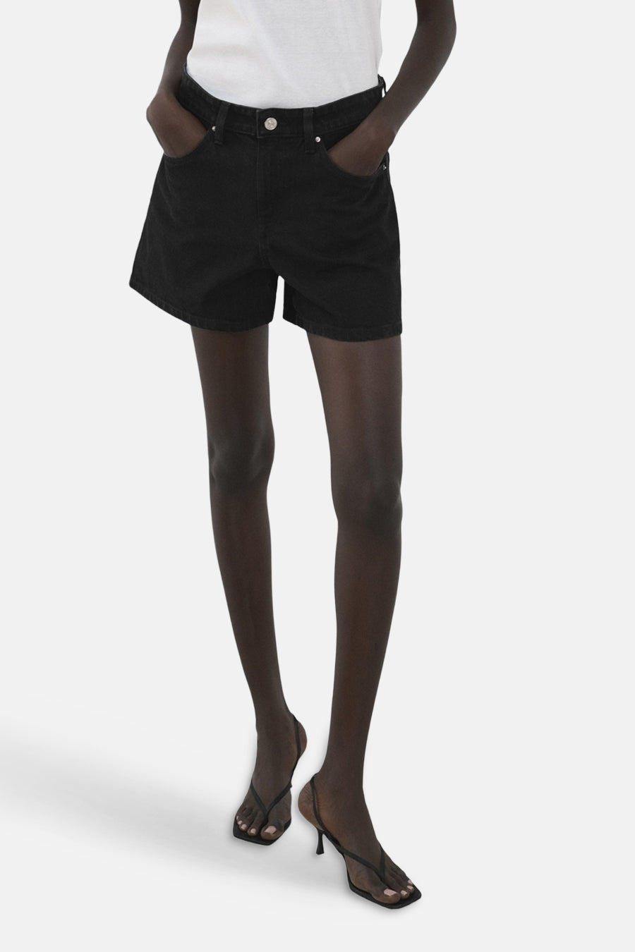 Short noir de MANGO, vu de dos avec une chemise blanche et une ceinture.
