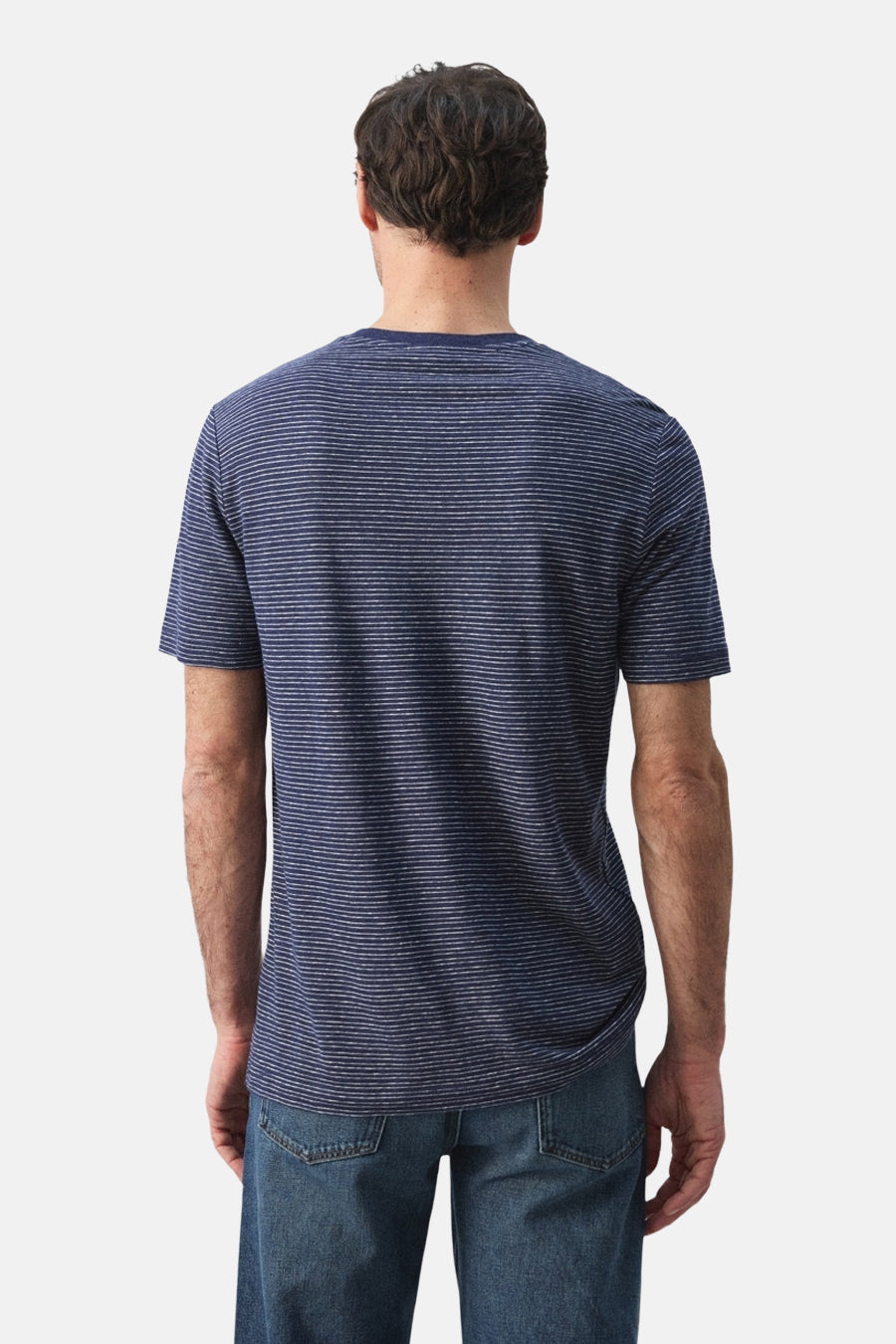 Blauw gestreept T-shirt van MANGO, gezien van achteren, gecombineerd met een jeansbroek.
