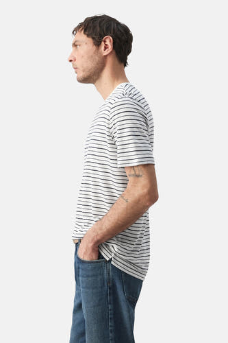 T-shirt multicolore de MANGO, à rayures horizontales, manches courtes et porté avec un jean bleu, en vue de côté.