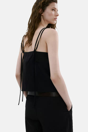 Zwarte top met spaghettibandjes van MANGO met strikdetails, achterzijde, gedragen op een zwarte broek.