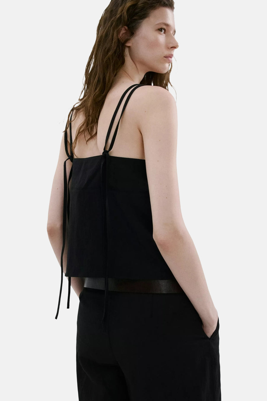 Zwarte top met spaghettibandjes van MANGO met strikdetails, achterzijde, gedragen op een zwarte broek.