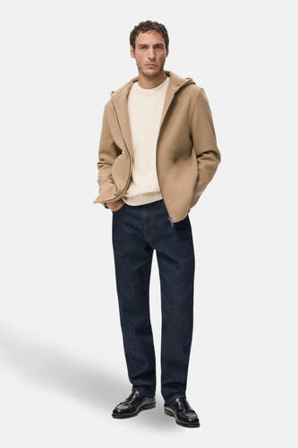 Manteau court beige de MANGO, porté avec un pull crème, des jeans noirs et des loafers en cuir noir.