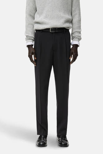 Pantalon noir de MANGO, dos, avec une texture lisse et associé à un pull gris.