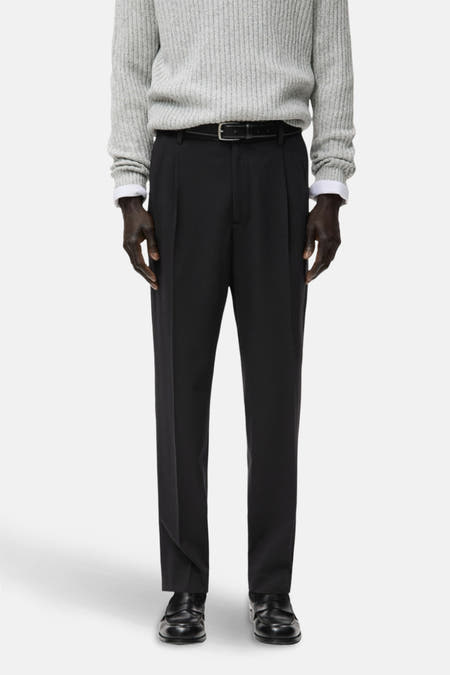 Pantalon noir de MANGO, dos, avec une texture lisse et associé à un pull gris.