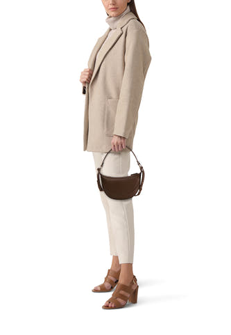 Kaki MANGO en épaules, avec texture en cuir, porté avec un pull beige et un pantalon blanc.