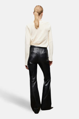 Ecru blouse met lange mouwen van MANGO, gecombineerd met een zwarte leren broek met wijde pijpen.