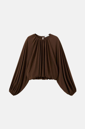 Blouse brune à longues manches de MANGO, avec une ligne de col pliée et des poignets élastiques.