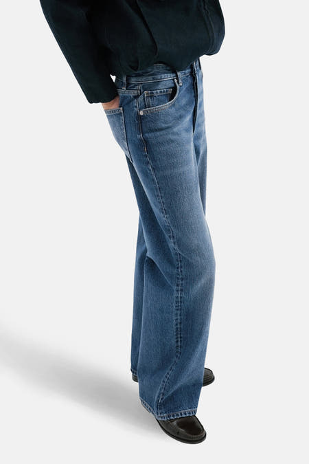 Jean droit en denim bleu moyen de MANGO, vu de dos avec des jambes larges et des poches.