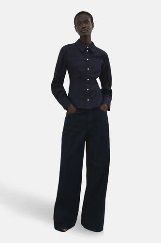 Chemise en jean bleu foncé à manches longues de MANGO, avec boutons blancs et coupe ample.