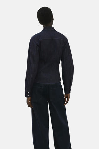 Donkerblauw denim overhemd met lange mouwen van MANGO, gezien van achteren met rechte, donkere jeans.
