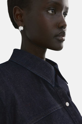 Chemise en denim bleu foncé à manches longues de MANGO, avec un col pointu et un bouton argenté.