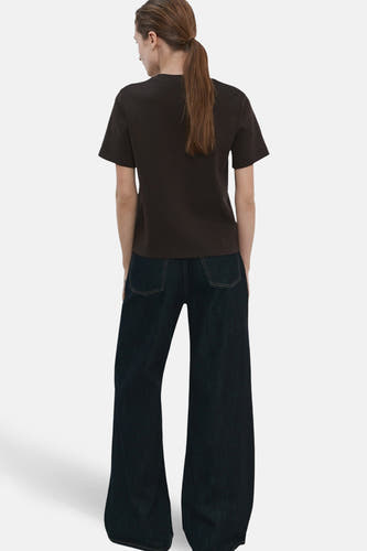 Bruin T-shirt met korte mouwen van MANGO, gezien van achteren, gecombineerd met een donkere jeans met wijde pijpen.