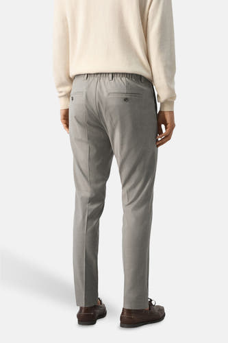 Beige broek van MANGO, gezien van achteren met elastische tailleband en bruine schoenen.
