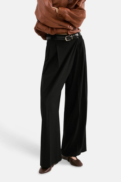 Pantalon noir de MANGO, à jambes larges et avec une ceinture noire à boucle dorée.