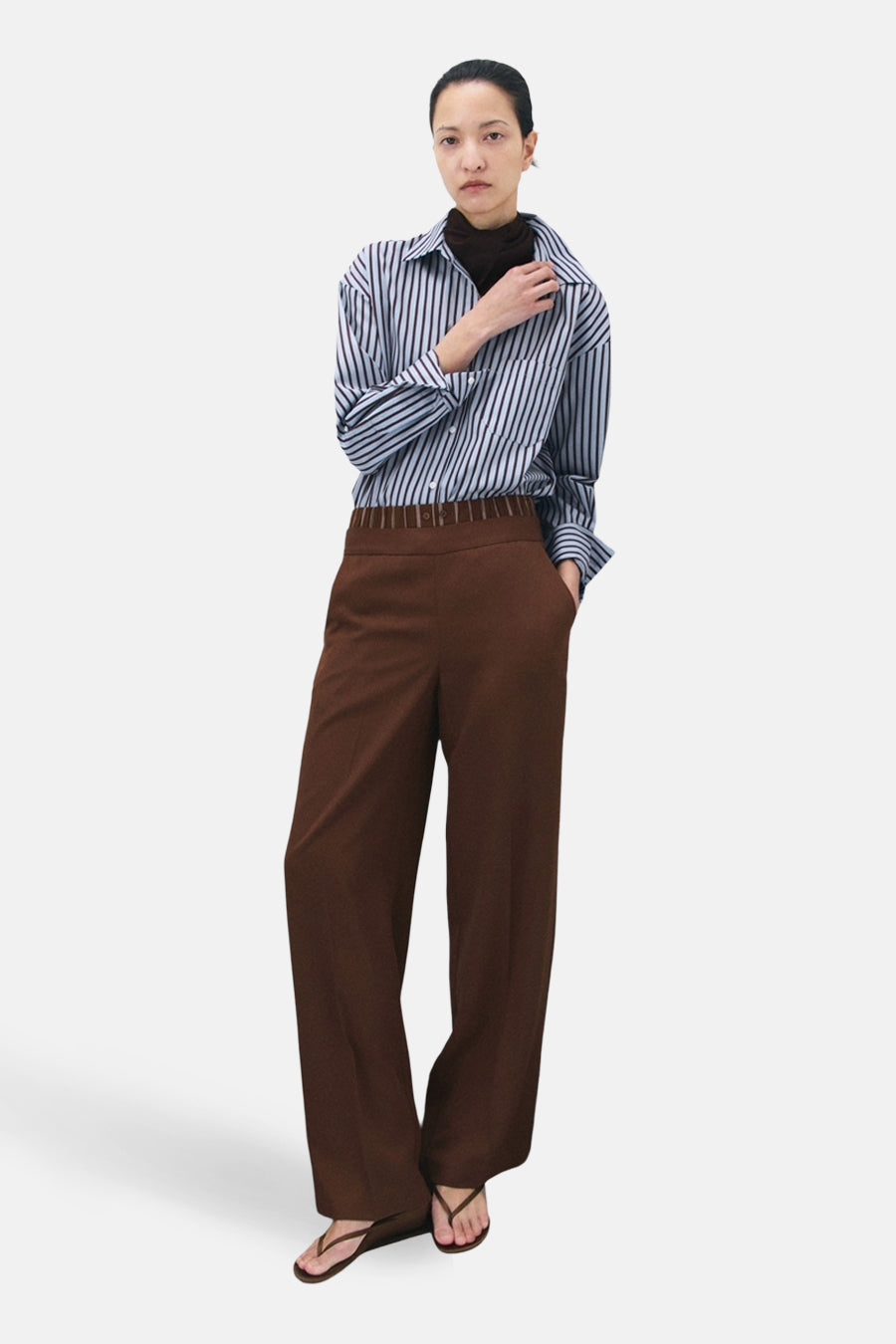 Chemise multicolore à manches longues de MANGO, portée avec un pantalon marron et des tongs marron.