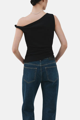 Zwarte top zonder mouwen van MANGO, met een asymmetrische halslijn en gedragen met een zilveren ketting en blauwe jeans.
