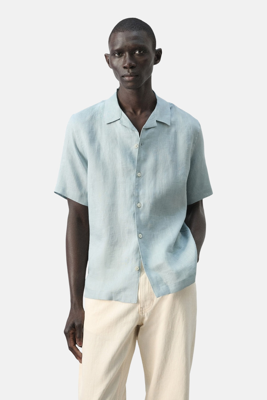 Chemise bleue à manches courtes de MANGO, vue de dos, avec un pantalon de couleur crème clair.