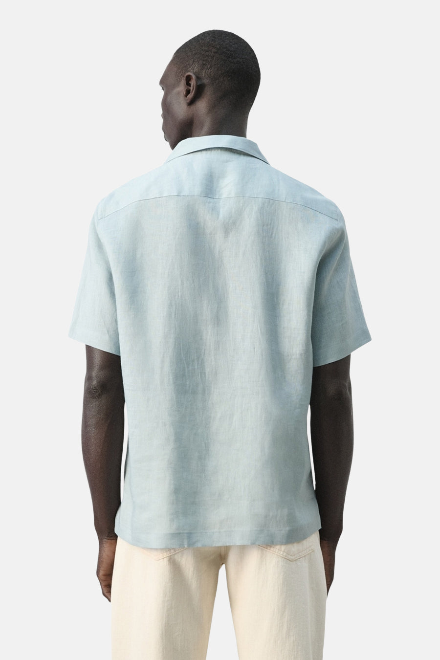 Blauw overhemd met korte mouwen van MANGO, gezien van achteren, met lichte crèmekleurige broek.