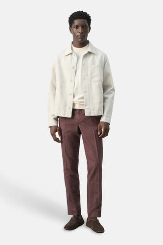 Veste courte écru de MANGO, à manches longues et fermeture boutonnée, portée avec un pantalon en velours côtelé bordeaux et des chaussures marron.