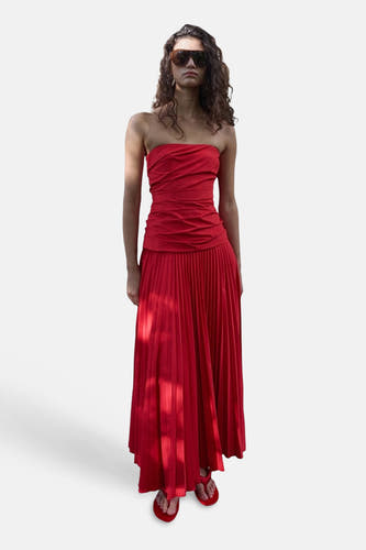 Robe courte bustier rouge de MANGO avec jupe plissée, portée par un mannequin les bras croisés.