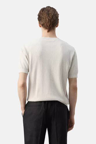 Ecru T-shirt met korte mouwen van MANGO, met geribbelde textuur, van achteren gezien en gedragen op een zwarte broek.