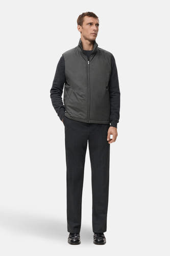 Gilet gris de MANGO, porté sur une chemise et un pantalon gris foncé, avec une fermeture éclair et des poches.