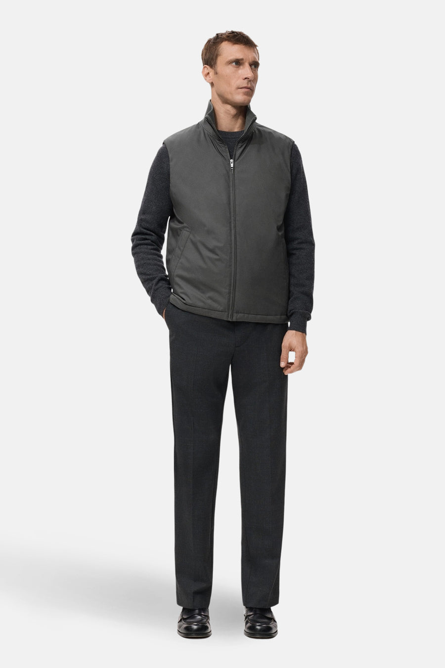 Gilet gris de MANGO, porté sur une chemise et un pantalon gris foncé, avec une fermeture éclair et des poches.