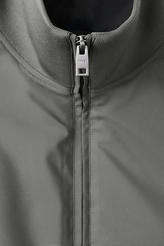 Gilet gris de MANGO, avec une texture lisse et une fermeture éclair argentée à l'avant.