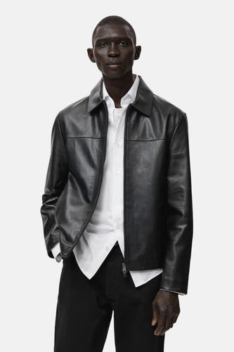 Manteau court noir de MANGO, côté dos visible, associé à un t-shirt blanc et des jeans noirs.