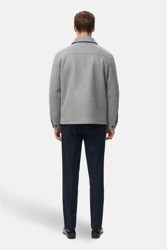 Grijze korte jas van MANGO, achterkant gezien, met donkere pantalon en zwarte schoenen.