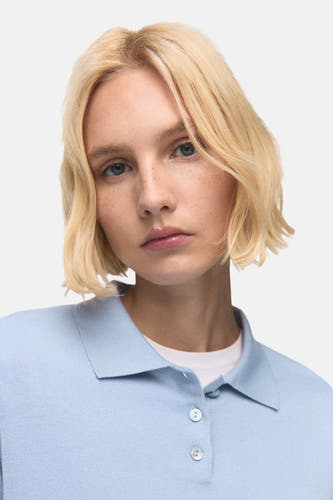 T-shirt bleu avec col rond de MANGO, porté sur un chemisier blanc à col rabattu.