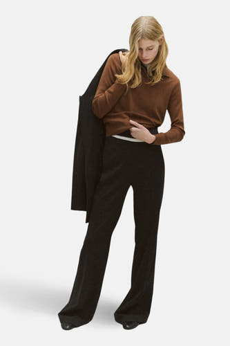 Sweat-shirt marron de MANGO, à longues manches, porté avec un pantalon noir et une veste sur l'épaule.