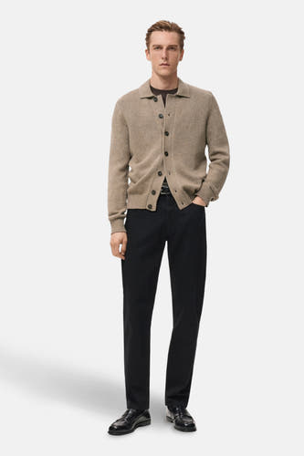 Gilet beige de MANGO, porté sur une chemise marron et associé à des jeans noirs et des loafers en cuir.
