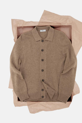 Gilet beige de MANGO, emballé dans une boîte avec du papier brun.
