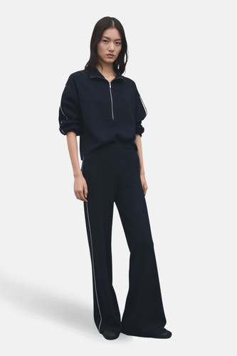 Pantalon bleu de MANGO, avec des jambes qui s'élargissent et une bande blanche sur le côté.