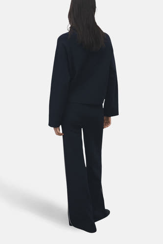 Blauwe broek van MANGO, met wijde pijpen en een contrasterende streep aan de zijkant, gezien van achteren.
