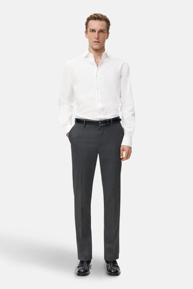 Chemise blanche à manches longues de MANGO, portée avec un pantalon gris et une ceinture noire, vue de face.