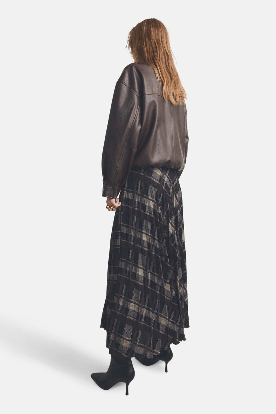 Lange multicolor rok van MANGO, met een geruite print, geplooide textuur, gecombineerd met een bruin leren jasje en zwarte laarzen.
