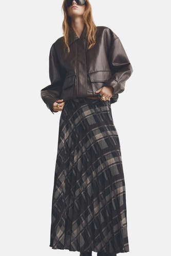 Long tutu multicolore de MANGO avec une imprimé large et un détail plissé, associé à une veste en cuir brun.