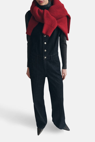 Combinaison de denim bleu marine de MANGO, vue de derrière, avec des manches longues et larges et une chemise sans manches sur un pantalon gris.