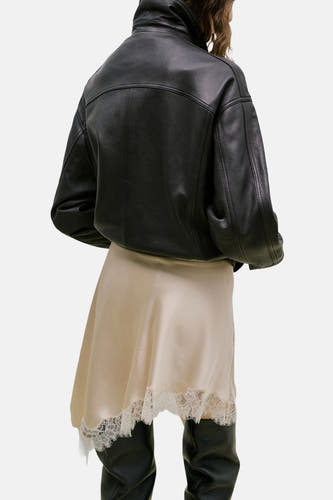 Korte beige rok van MANGO, met kanten rand en gedragen met een zwarte leren jas en hoge laarzen.