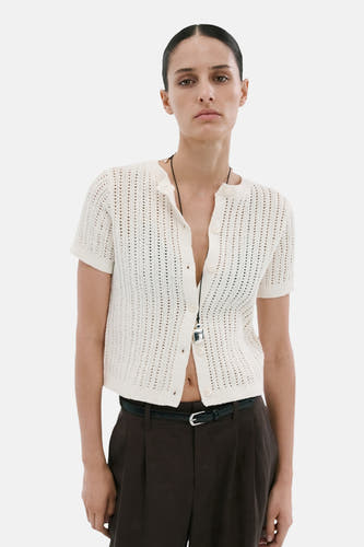 Gilet ajouré blanc de MANGO à manches courtes, vu de dos sur un mannequin portant un pantalon foncé.